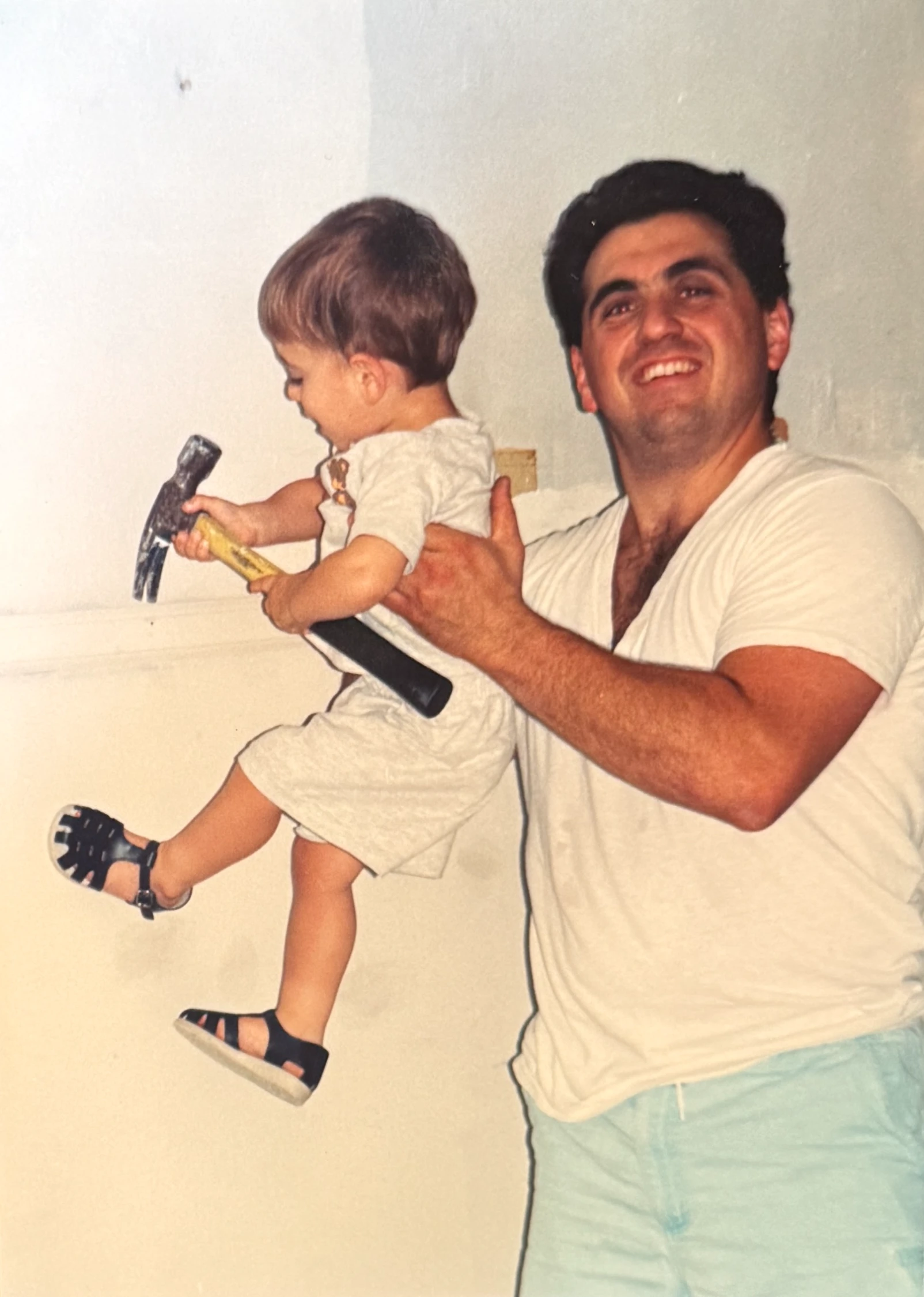 Dave Sainato holding a young Joe Sainato with a hammer