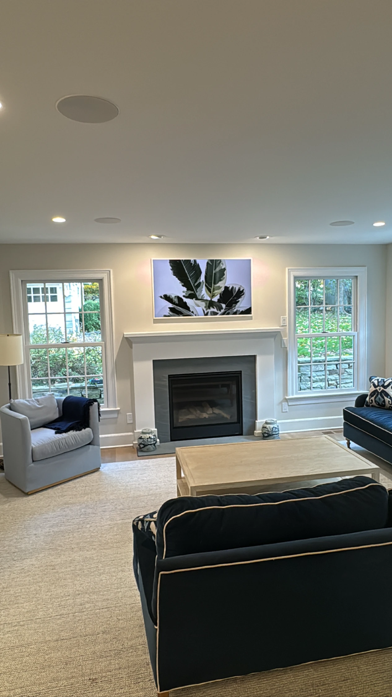 Frame TV over fireplace with in-ceiling speakers in a family room