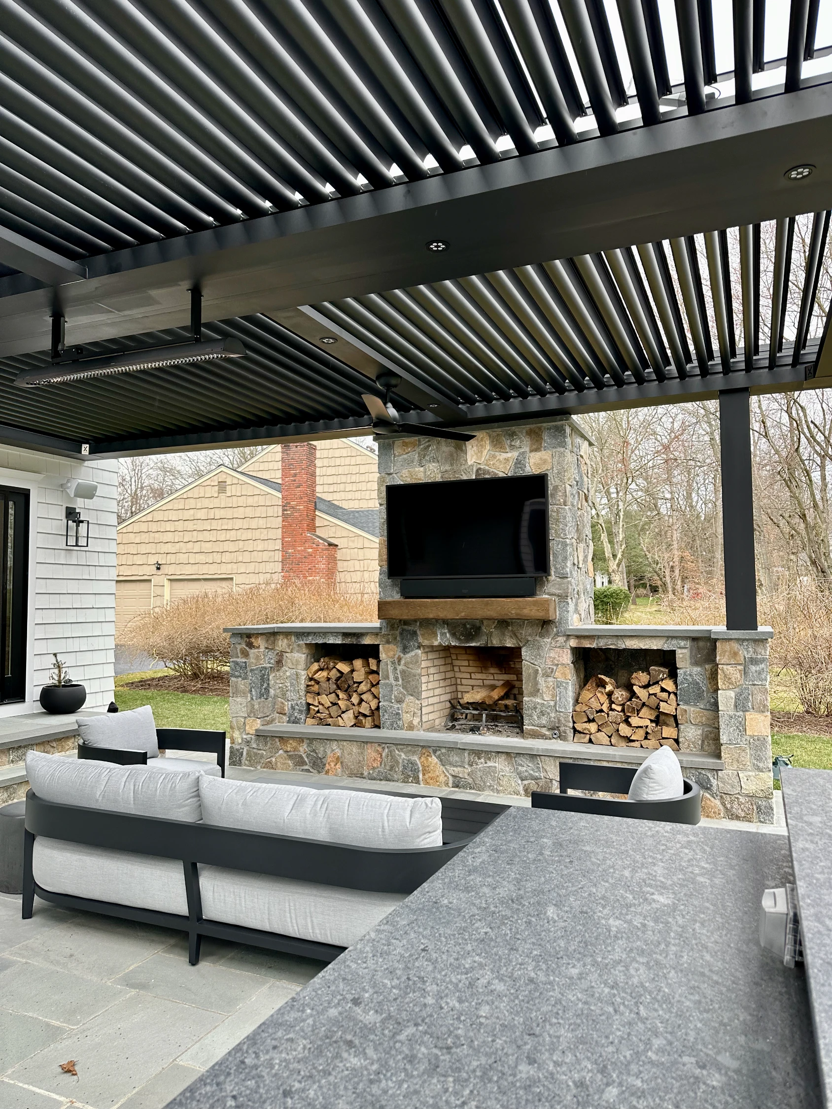 Outdoor fireplace seating area with mounted TV